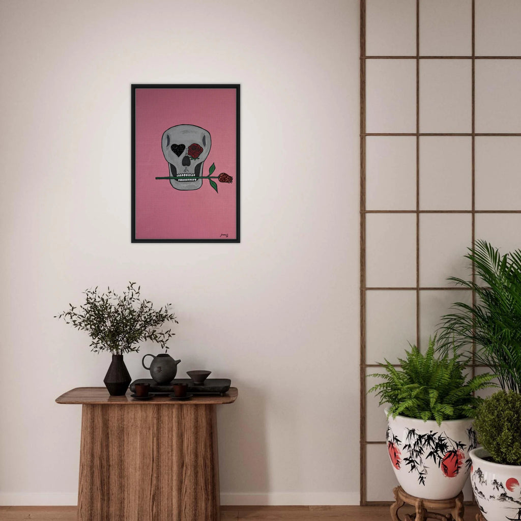 Framed 24×36 Johnny X canvas showing a gray skull on pink field, one eye a black heart, the other a red rose, a rose between its teeth.