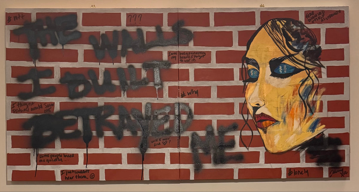 Johnny X’s Alley of Broken Dreams, a 60 × 30-inch diptych featuring a red brick wall covered in black graffiti, handwritten thoughts, and emotional fragments, alongside a striking female face in gold, blue, and black, exploring isolation, heartbreak, and the walls we build to protect ourselves.
